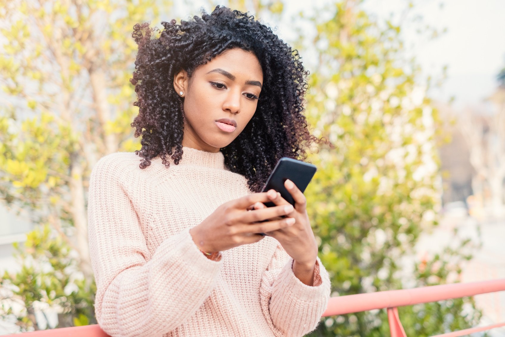 Upset black girl holding mobile phone outdoor